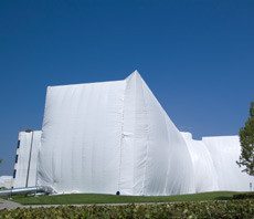 Large building covered in white fumigation tent.